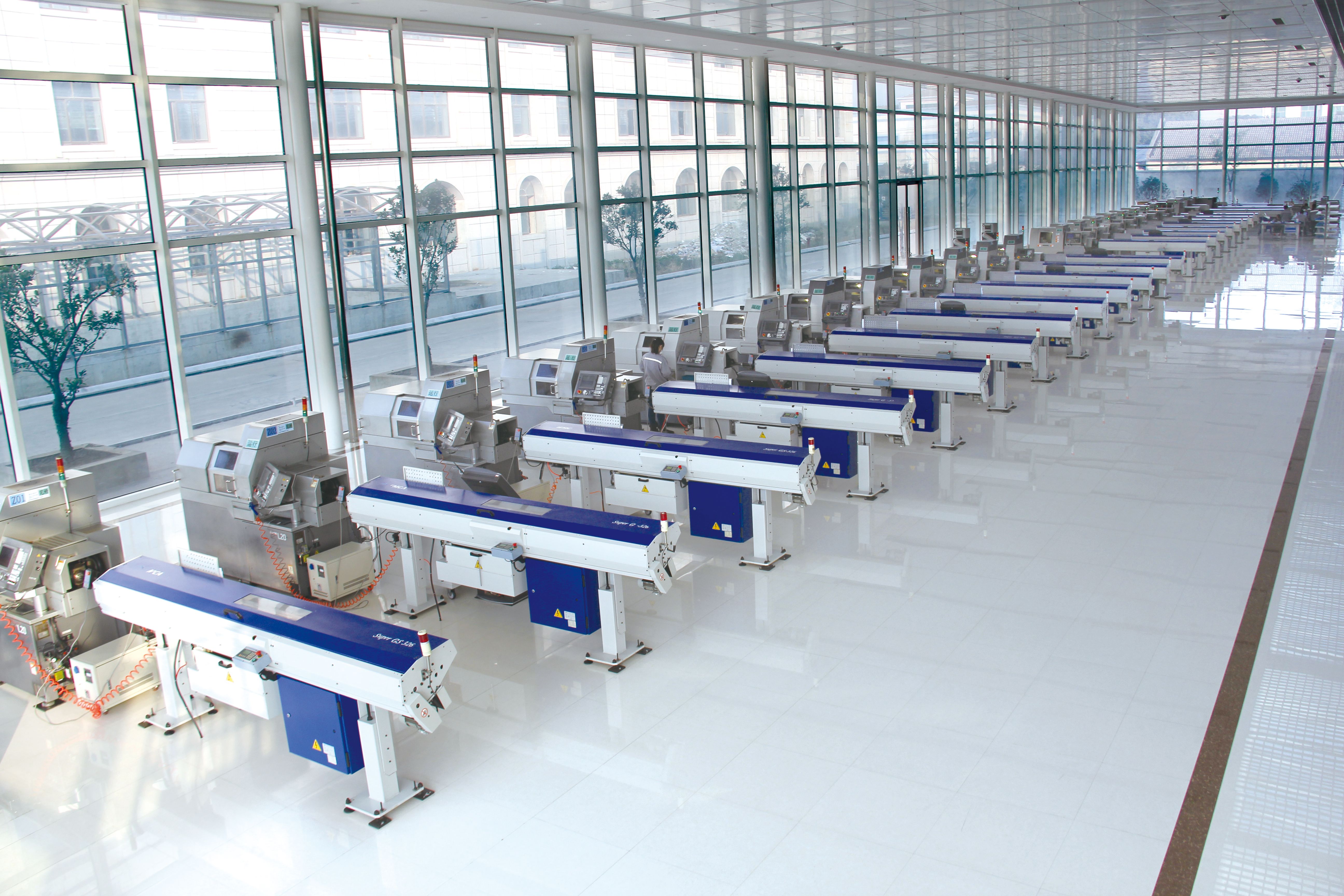 Rows of Citizen Cincom automatic CNC lathes with blue bar feeders in Kangli's daylit Swiss-turning hall