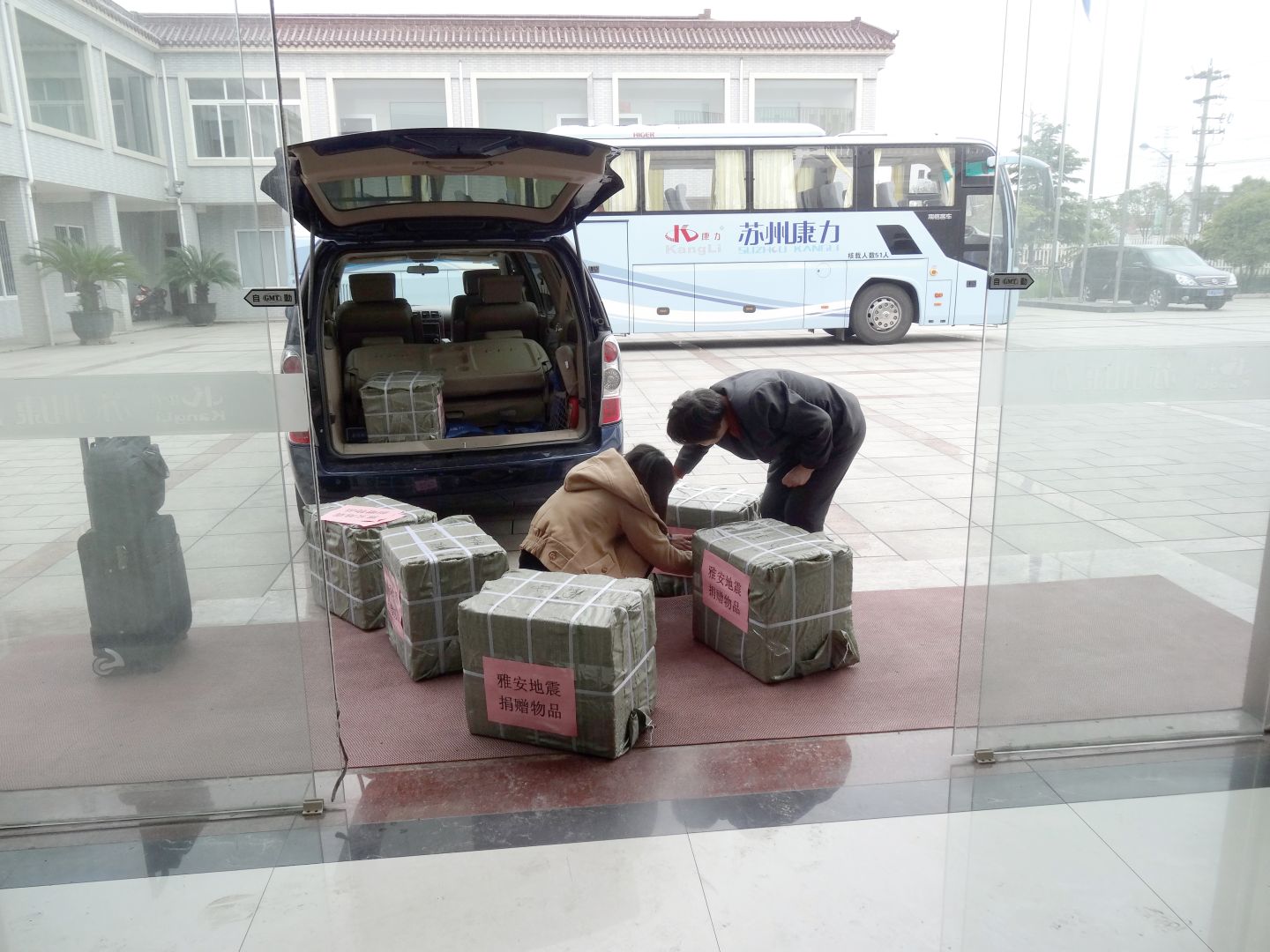 Kangli staff loading sealed relief boxes labelled for the Ya'an earthquake donation into a vehicle outside company headquarters