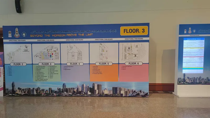 Blue freestanding directional signboard with floor maps and schedule information on a polished foyer floor.