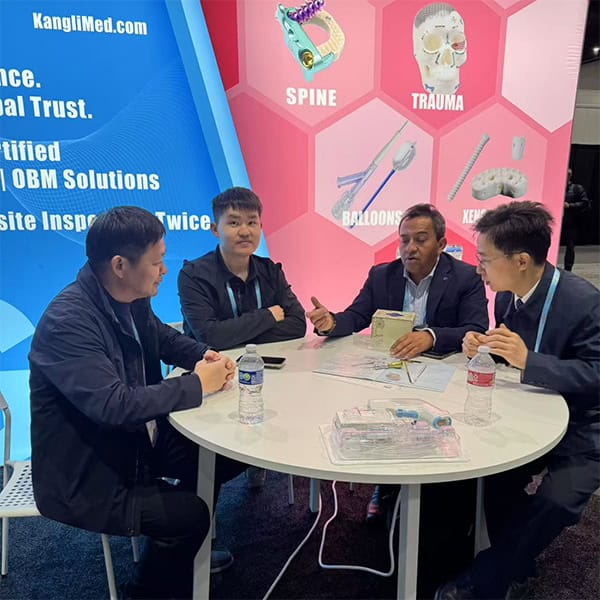 Four people sit around a white round table at an exhibition stand with blue and pink graphic backdrops.