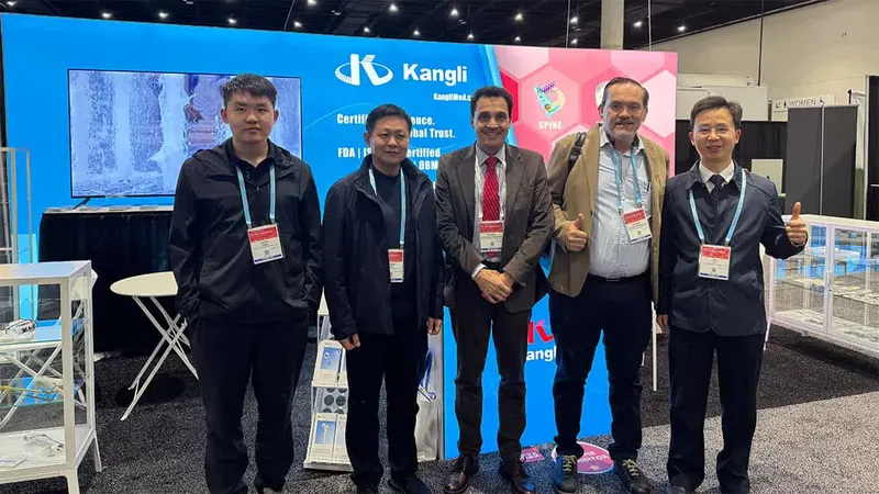 Five people stand in a row at a trade-show booth with display cases, a monitor, a brochure holder, and a branded backdrop.