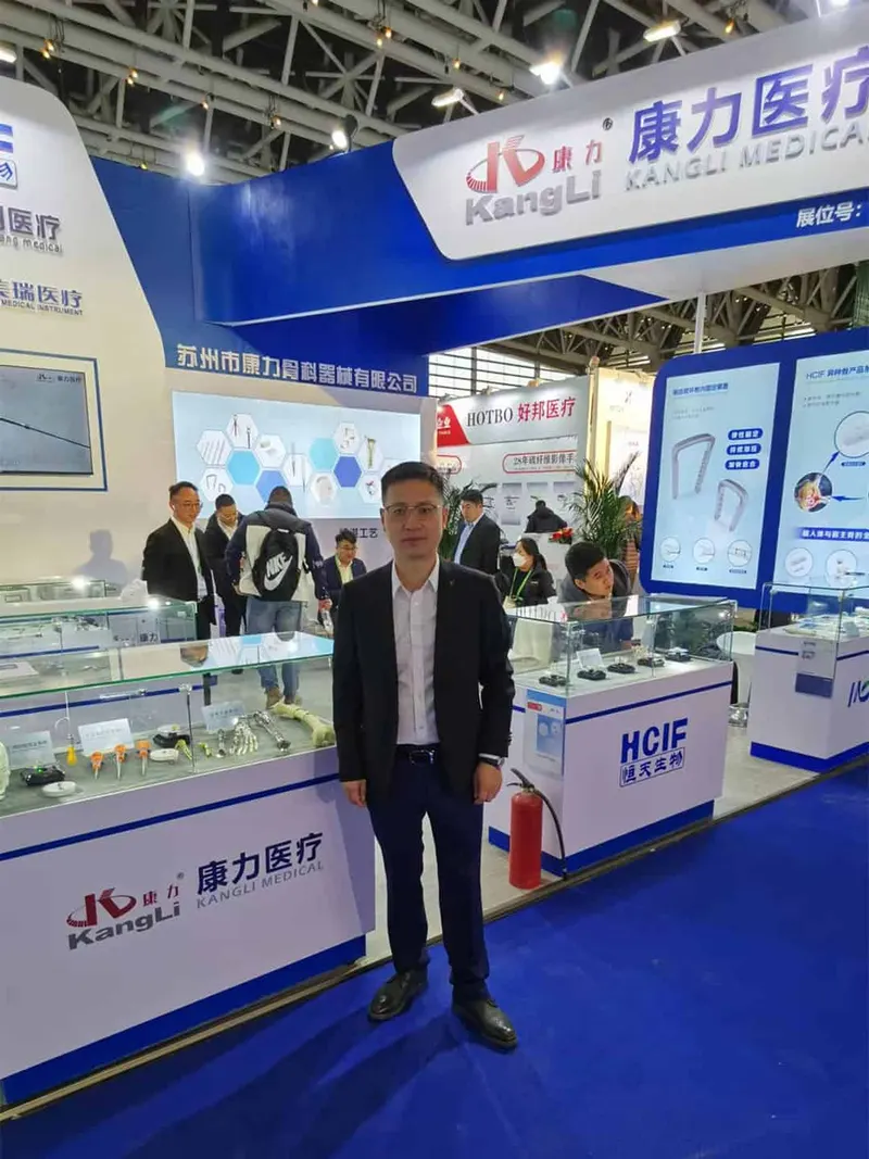 One participant stands in front of a blue-and-white exhibition stand while about eight others examine displays or speak behind the counters.