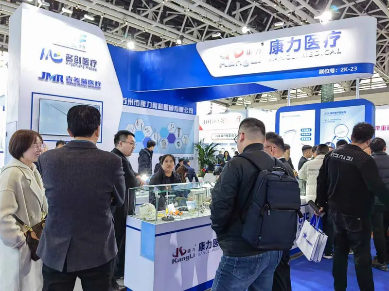 About twelve attendees stand around a white and cobalt-blue exhibition stand with display counters and product cases.