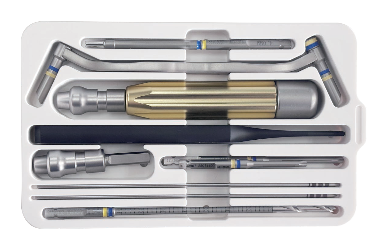 White compartmented tray containing nine visible metal instrument assemblies, including banded silver pieces, a gold-bodied assembly, and a dark tapered rod
