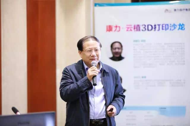 One speaker holds a handheld microphone in front of a white presentation backdrop with blue bands.