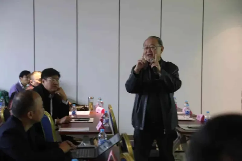 Seven participants attend a classroom-style workshop while a speaker stands at the front.