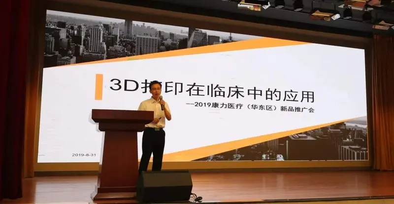 One speaker stands at a lectern holding a microphone before an illuminated presentation screen.