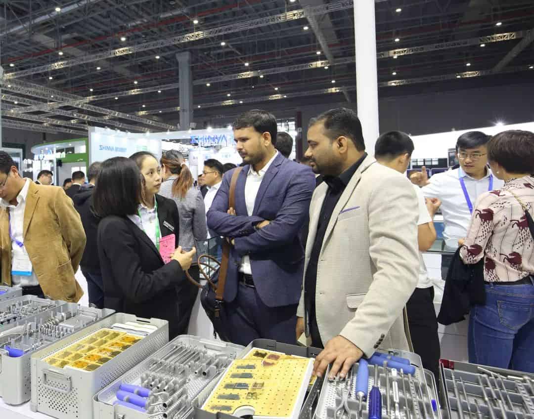 At least nine participants stand around open display counters at a crowded exhibition stand.