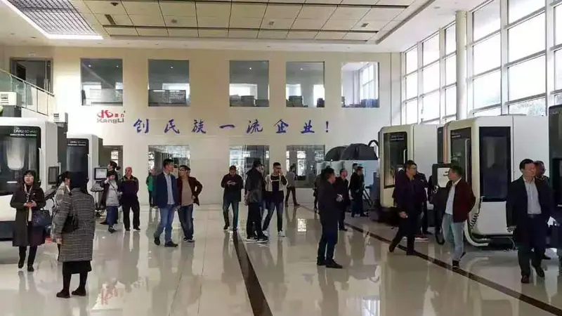 About 20 participants stand or walk among large enclosed machines in a bright indoor industrial display hall.