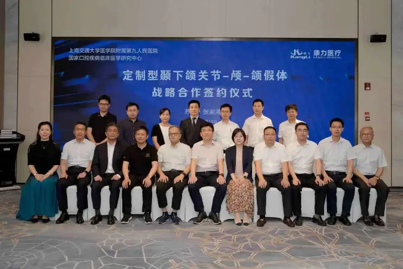 Eighteen participants pose in two rows indoors, with eleven seated in front and seven standing behind them.
